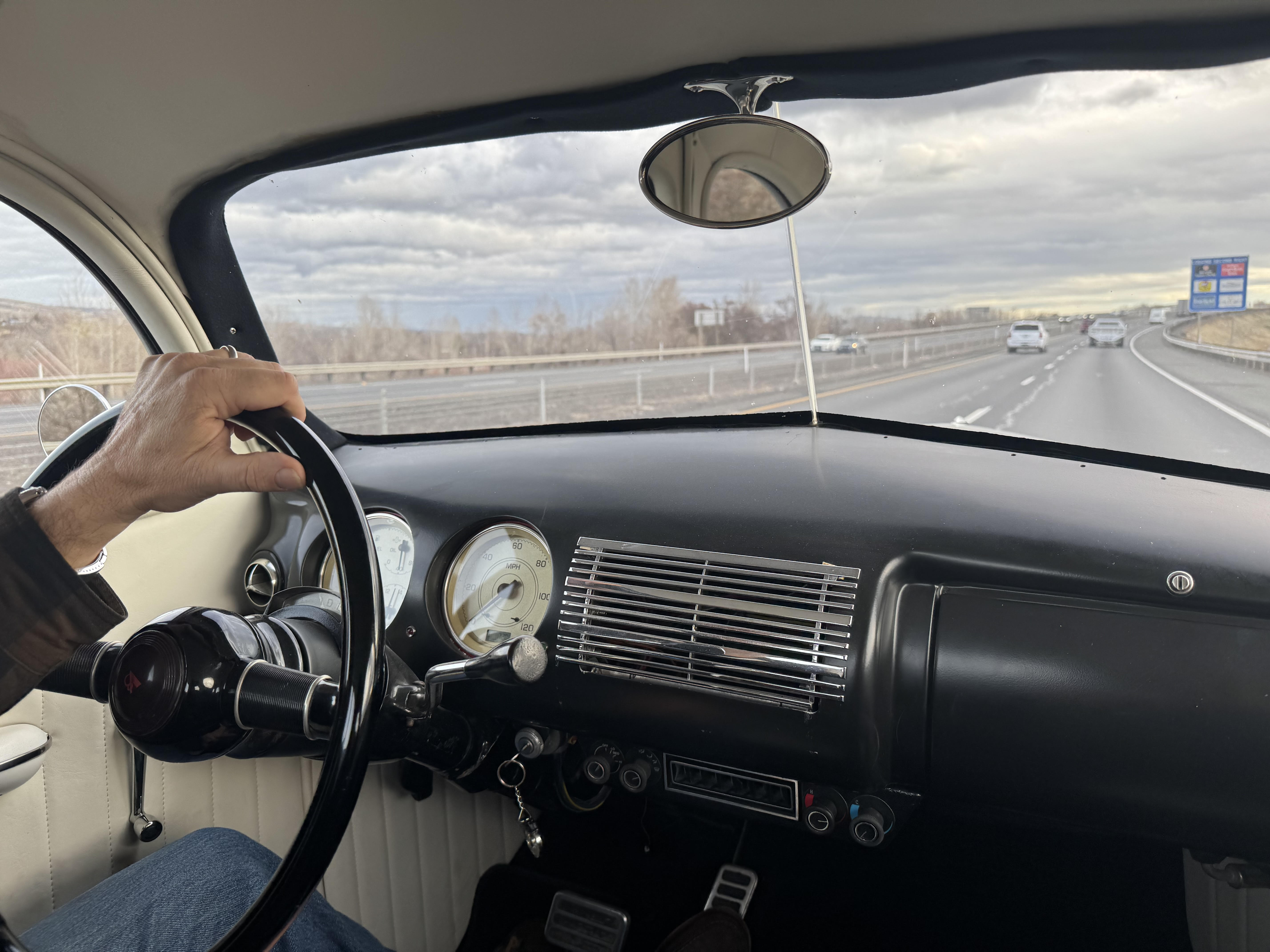 Classic car interior - hands on wheel, open road ahead