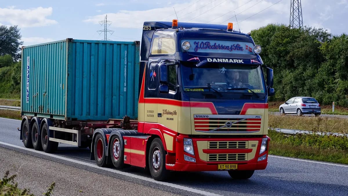 A semi-trailer truck hauling a shipping container on a main road